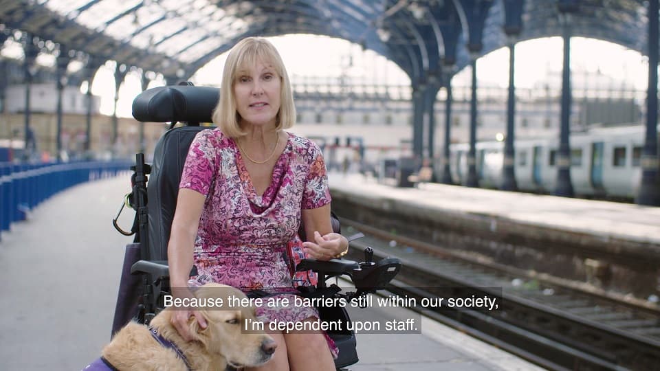 Woman in wheelchair with dog at train station