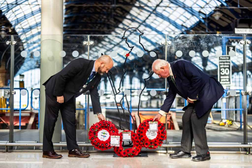 Two men laying poppy wreaths at Brighton station