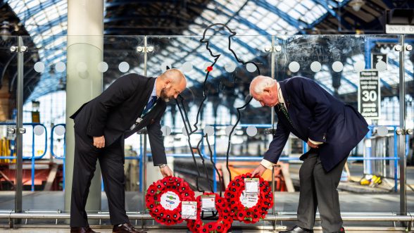 Two men laying poppy wreaths at Brighton station