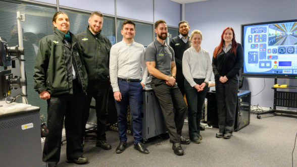 Eight train apprentices standing in a railway control room